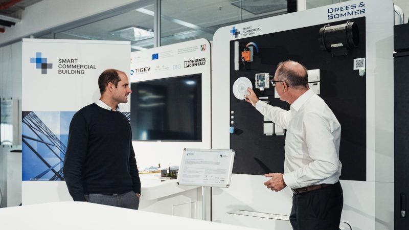 Zwei Männer demonstrieren an einem Messestand SmartBuilding.